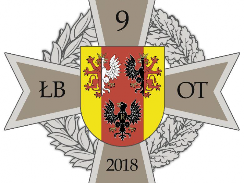 Na zdjęciu odznaka 9 ŁBOT. Krzyż i tarcza. w środku tarczy trzy orły z koronami