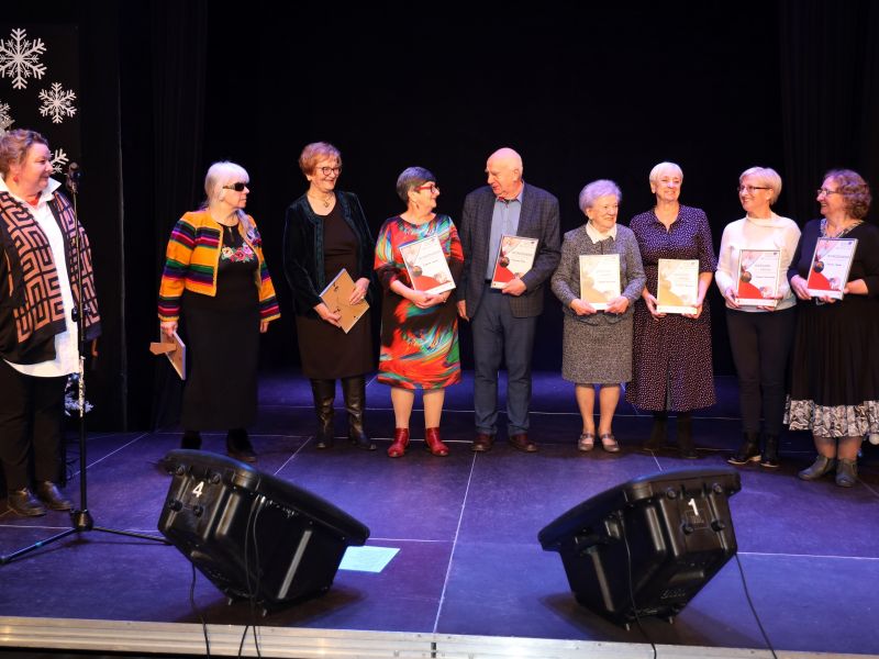 Na zdjęciu seniorzy, którzy wzięli udział w Przeglądzie Twórczości Seniorów 60 plus. Stoją na scenie z przyznanymi nagrodami