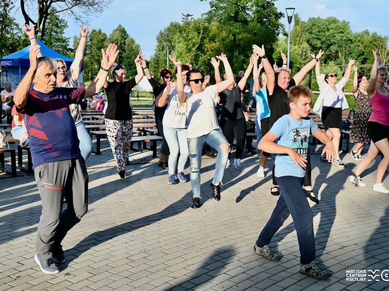 Na zdjęciu grupa ludzi tańczy przed amfiteatrem na przystrani miejskiej podczas fajfu tanecznego zorganizowanego przez Miejskie Centrum Kultury