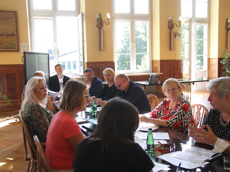 Na zdjęciu, przy długim stole siedzi 10 osób - rozmawiają