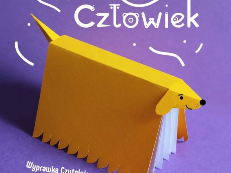 Na zdjęciu plakat projektu bibliotecznego Wyprawka Czytelnicza dla Przedszkolaka. Na plakacie grafika - książka modelowana na psa jamnika