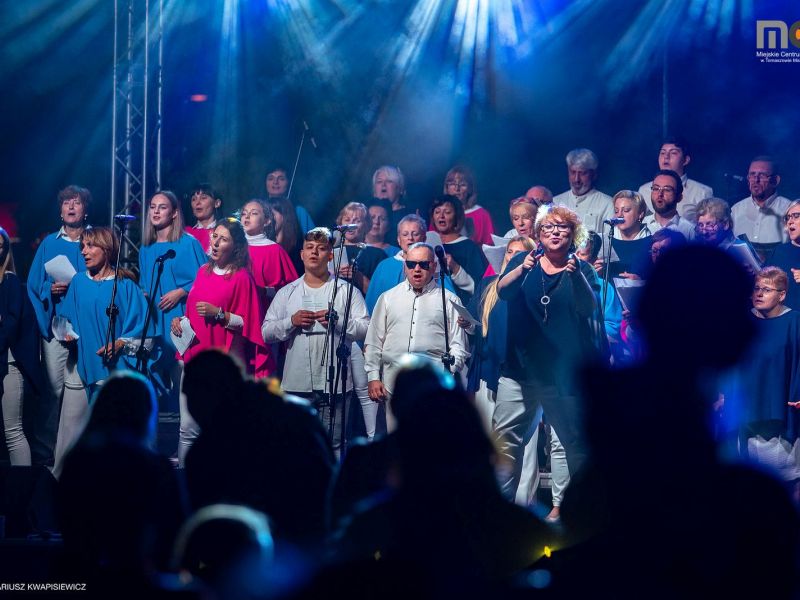 zdjęcie przedstawia śpiewajacych ludzi na scenie podczas koncertu  zrealizowanego w ramach projektu Rozśpiewaliśmy Tomaszów