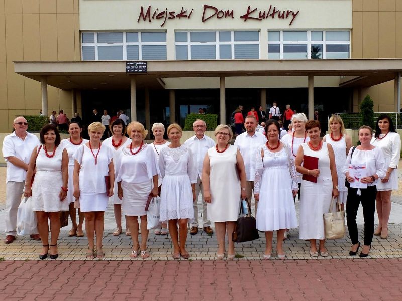 kobiety w białych sukienkach stoją przed budynkiem