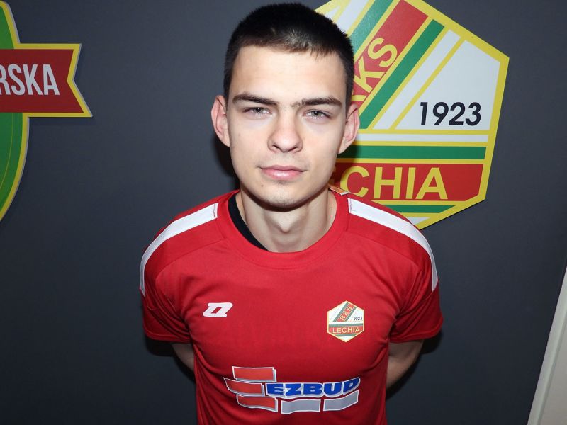 Na zdjęciu nowy zawodnik Lechii Tomaszó pozujący do zdjęcia na tle klubowego logo