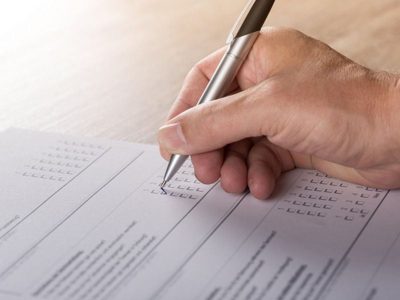 Na zdjęciu ręka człowieka wypełniającego ankietę przy pomocy długopisu