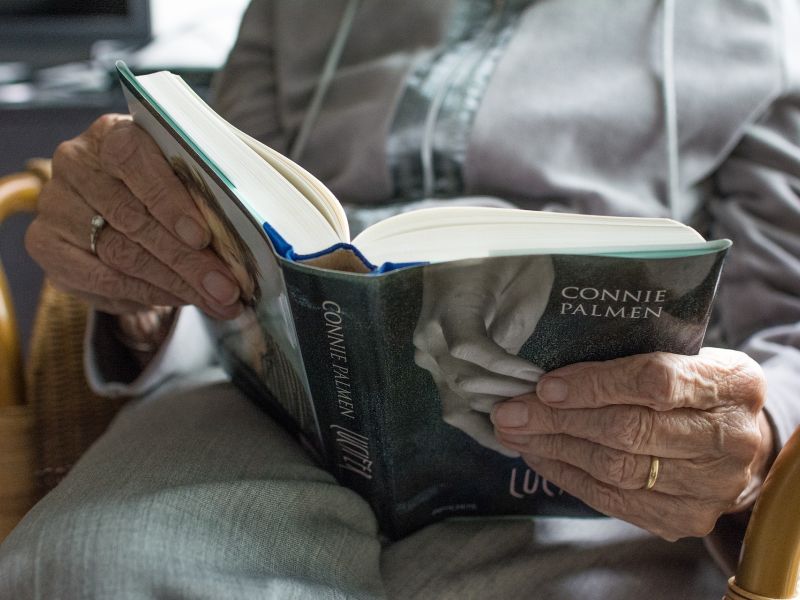 na zdjęciu widać ręce starszej kobiety trzymające książkę