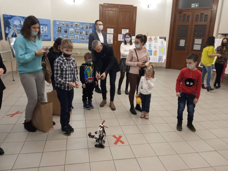 Na zdjęciu grupa laureatów konkursów zrealizowanych w ramach projektu goLEM 2021 bawi się sterowanym robotem w holu biblioteki