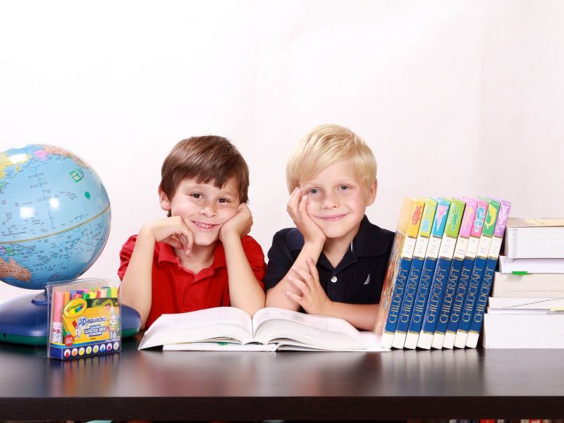 Na zdjęciu dwójka uczniów klasy pierwszej przy biurku, na którym ustawione sa ksiązki i globus