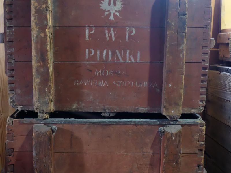 Na zdjeciu dwie drewniane skrzynie z II wojny światowej na ładunki wybuchowe, ustawione jedna na drugiej. Obecnie to eksponaty Skansenu Rzeki Pilicy