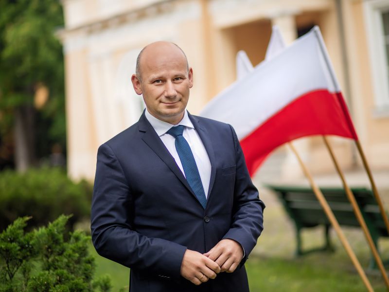 Na zdjęciu prezydent Marcin Witko na tle biało-czerwonej flagi. W głębui budynek muzeum w Tomaszowie Mazowieckim