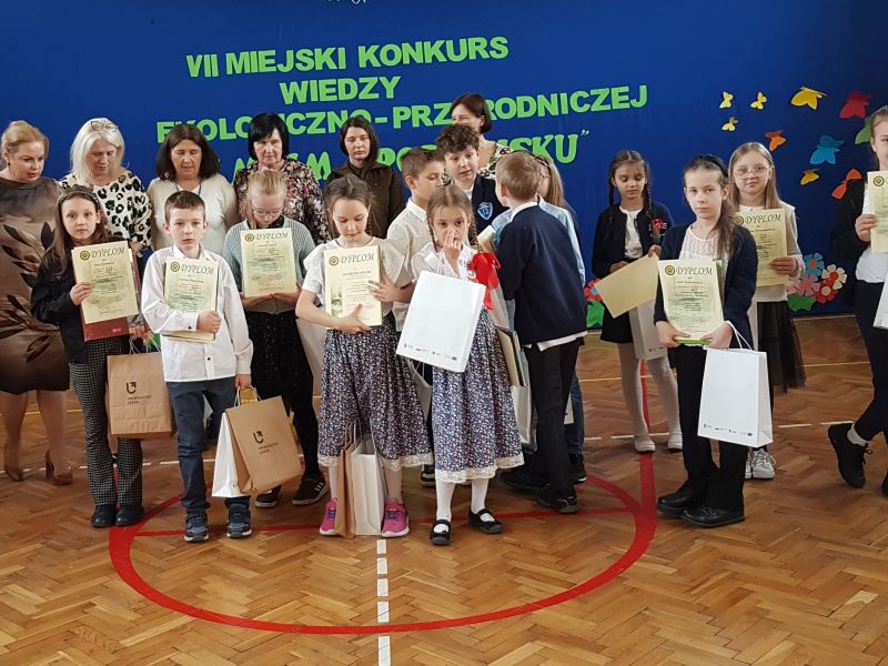 Na zdjęciu laureaci konkursu wiedzy ekologicznej w Szkole Podstawowej nr 13. Zdjęcie grupowe, laureaci z dyplomami i nagrodami na sali gimnastycznej szkoły