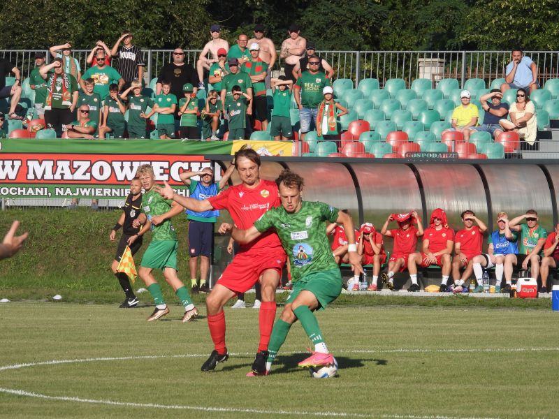 Na zdjęciu zawodnik Lechii Tomaszó walczy o piłkę w meczu futbolowym z zawodnikiem drużyny przeciwnej. W tle publiczność na trybunach