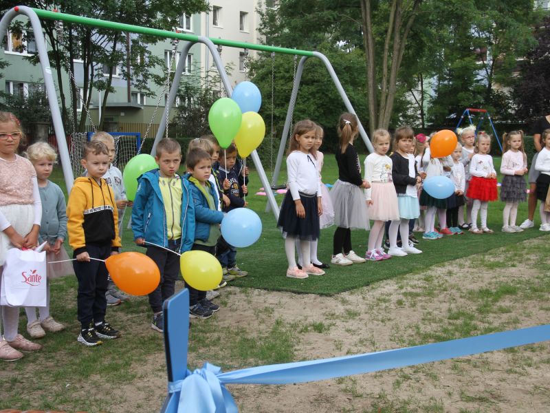 Na zdjęciu przedszkolaki z Przedszkola nr 20 na nowym placu zabaw. Zdjęcie z otwarcia placu, dzieci trzymają w rękach baloniki